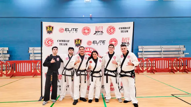 Galvan's Martial Arts instructors in black belts standing in front of the Elite Team banner